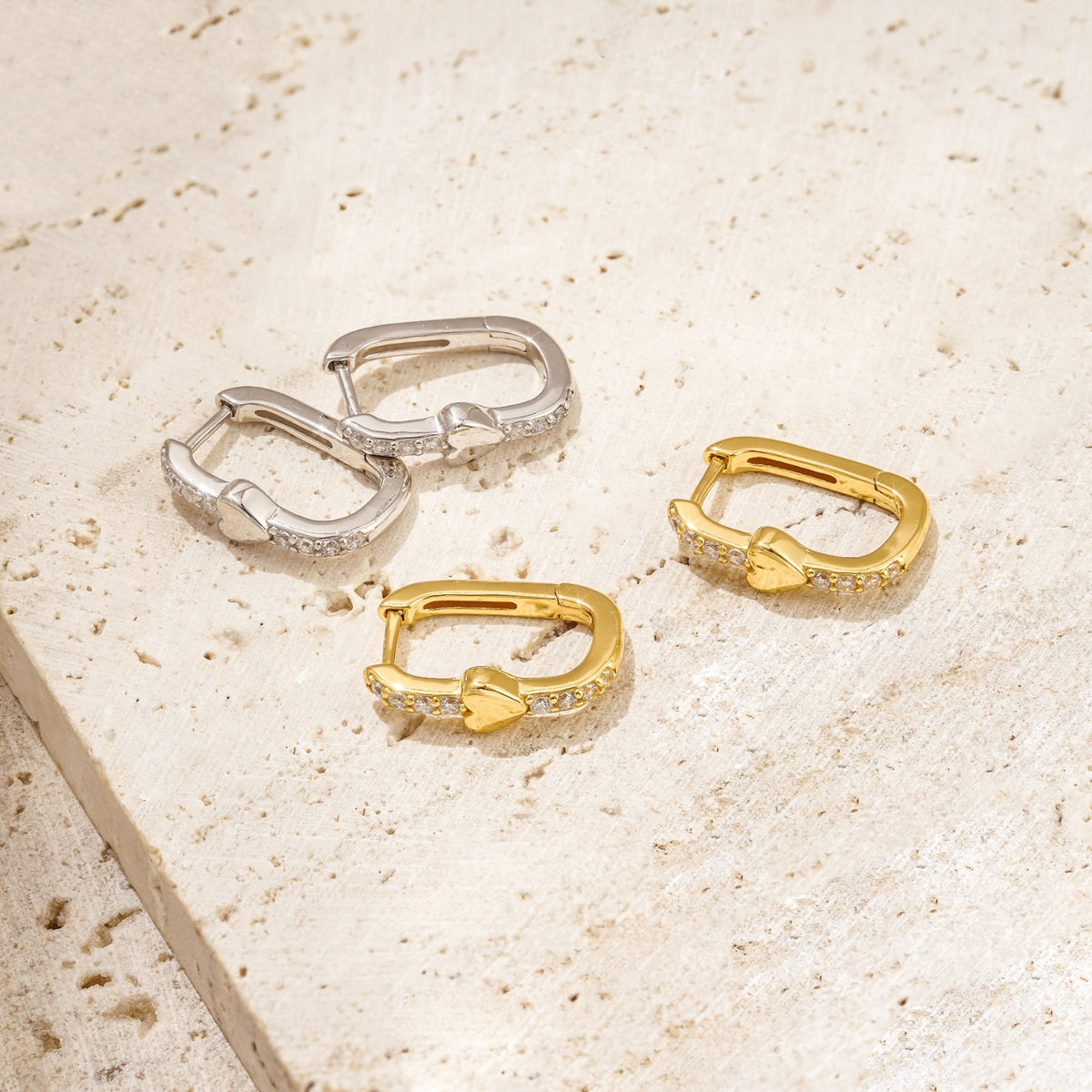 unique earrings with a dainty gold heart amid white zirconia stones. These hoop earrings have a unique shape. Available in gold and silver. 
