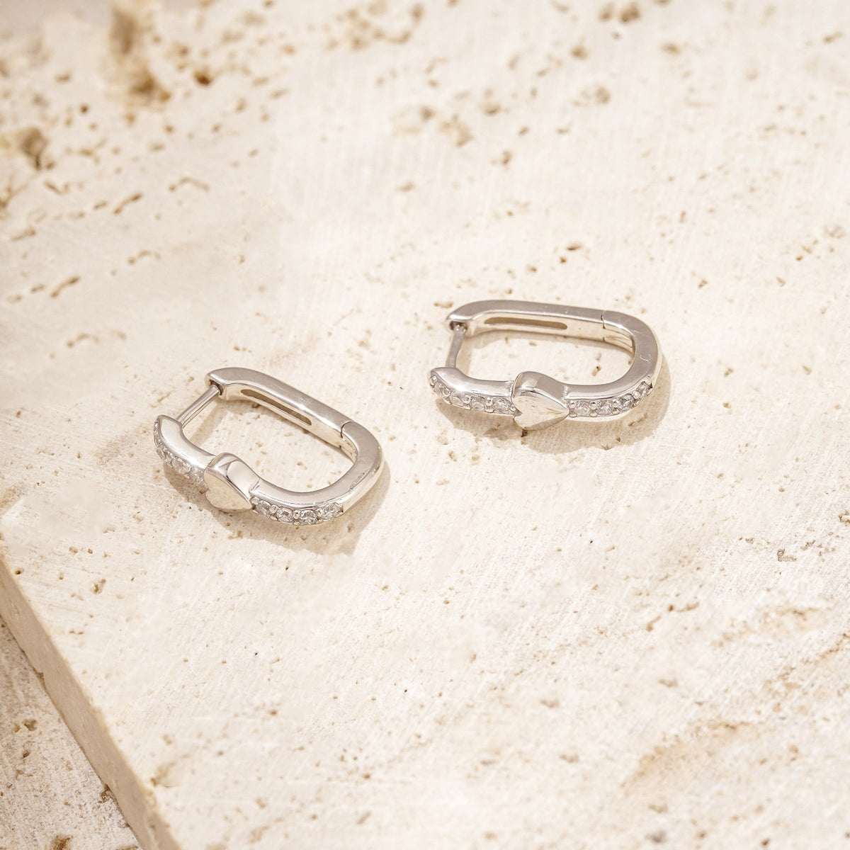 unique earrings with a dainty silver heart amid white zirconia stones. These hoop earrings have a unique shape. 