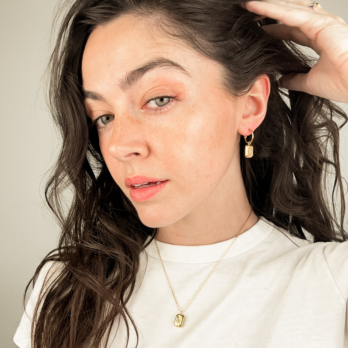 the poise necklace is a minimal piece of jewellery. The necklace has a dainty chain and the pendant is a rectangle shaped charm that has a star embellished at it's centre. The poise necklace also has matching earrings, as seen here. 