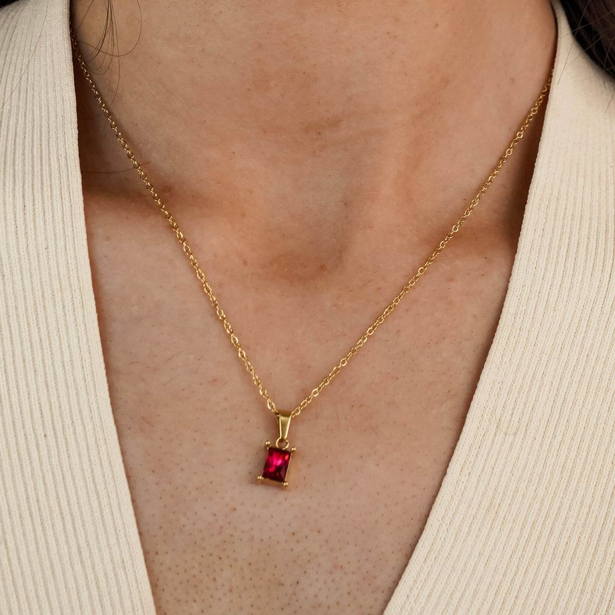 this rubina necklace features a gold stainless steel chain and one single red stone. The stone is an emerald cut stone in the colour of a ruby. 