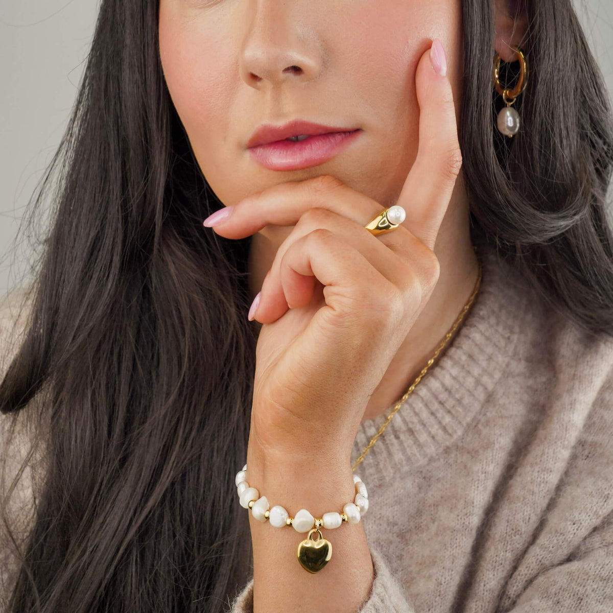 gold water resistant ring with a single pearl embedded in it.  photographed on a model wearing a pearl bracelet and pearl earrings also.