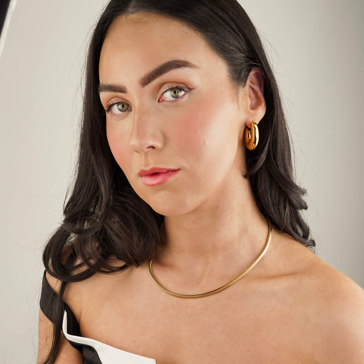 textured herringbone snake chain in gold plating available to shop at Mettle & Bloom. The Rhea chain is worn here by a model who has styled the Rhea chain with the Command hoop earrings. 