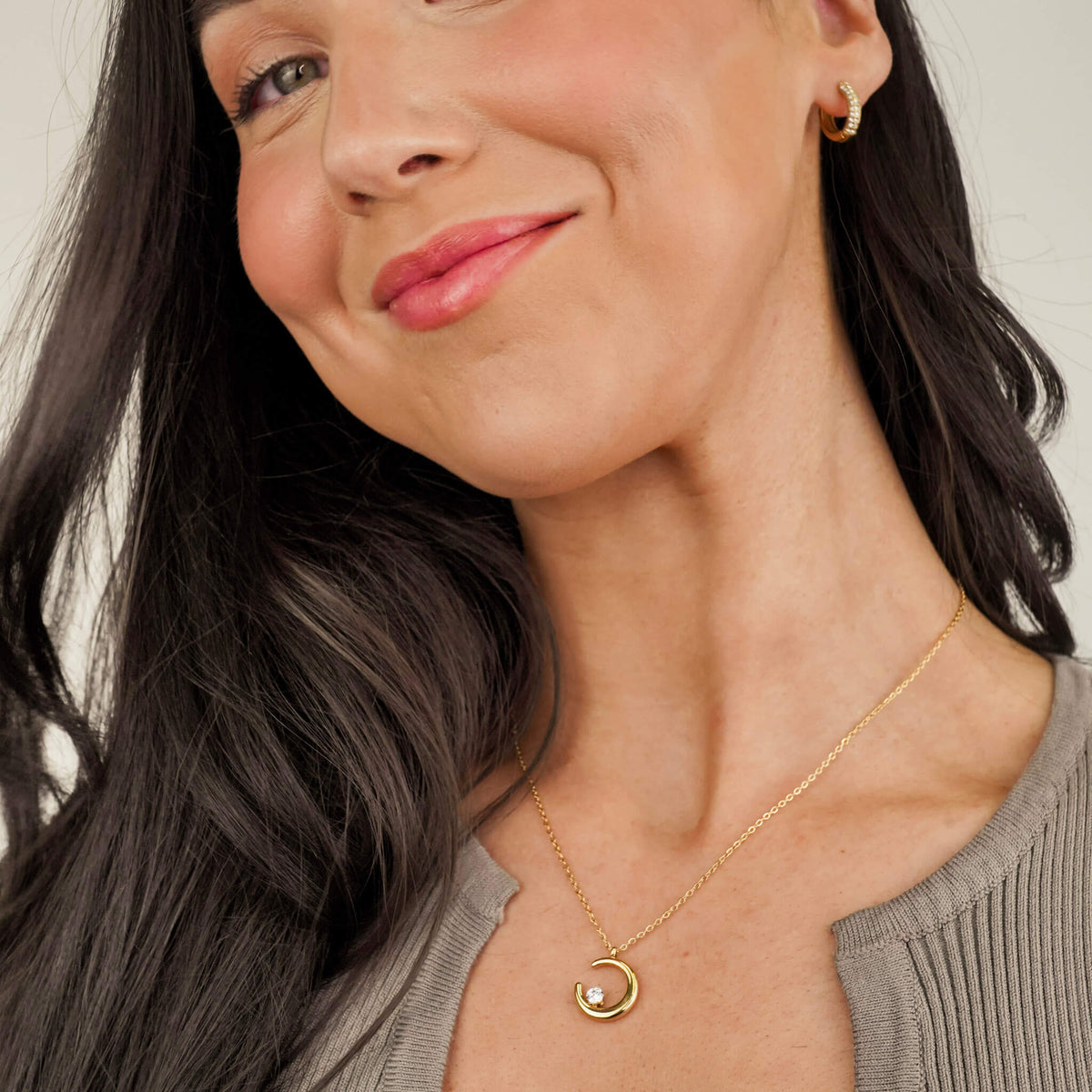 gift ideas for her: the crescent moon necklace from Mettle & Bloom is a perfect gift idea for her. The crescent shaped pendant hangs on a dainty chain and the focal point is the white zirconia stone that sits on the crescent moon like a bright, shining star.  It is sold individually and in the Illuminate bundle with the radiance hoops, as seen here. 