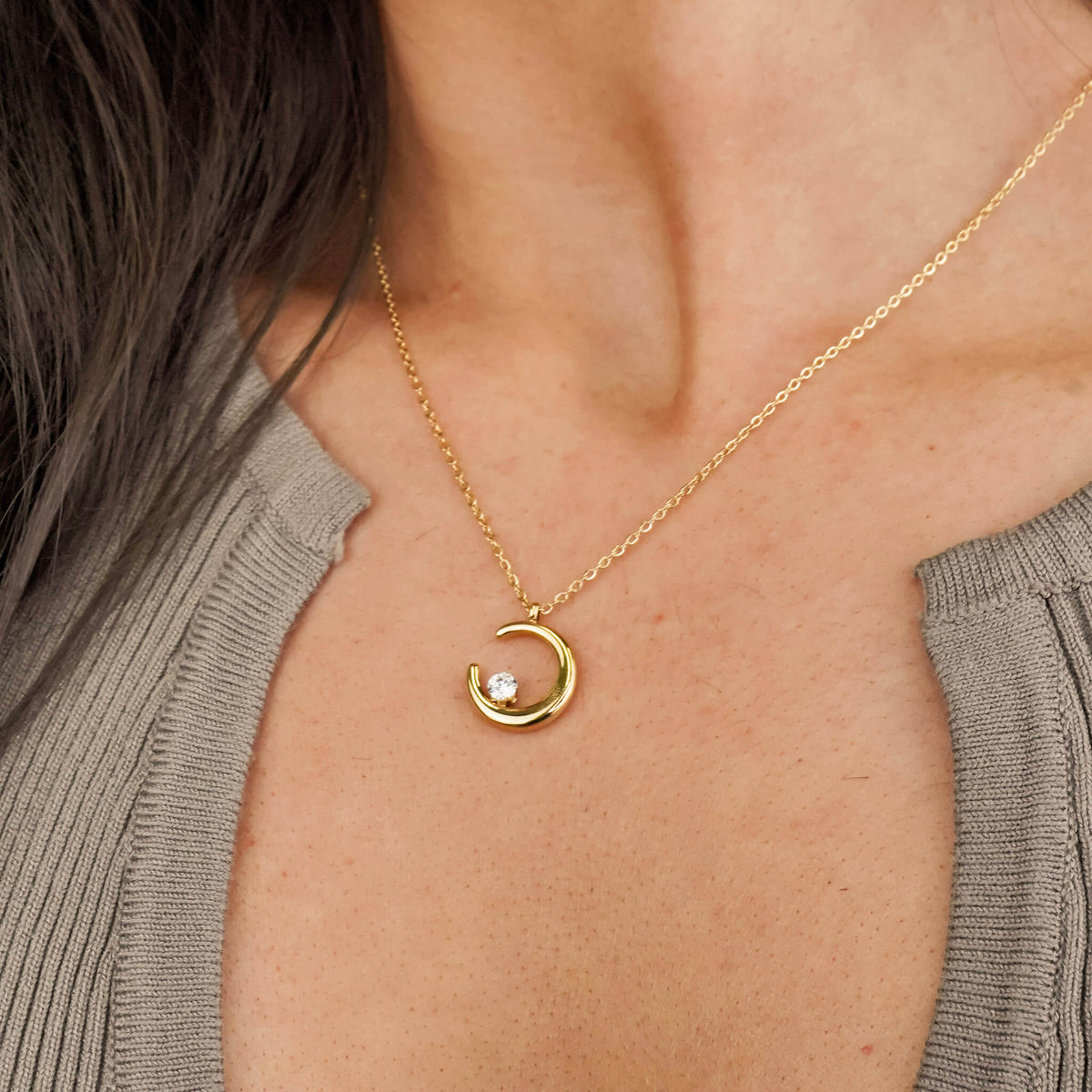 gift ideas for her: the crescent moon necklace from Mettle & Bloom is a perfect gift idea for her. The crescent shaped pendant hangs on a dainty chain and the focal point is the white zirconia stone that sits on the crescent moon. 