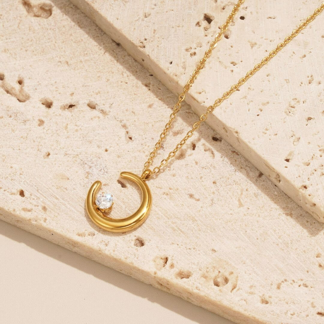 gift ideas for her: the crescent moon necklace from Mettle & Bloom is a perfect gift idea for her. The crescent shaped pendant hangs on a dainty chain and the focal point is the white zirconia stone that sits on the crescent moon like a bright, shining star. 