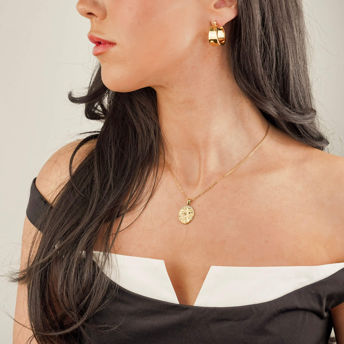 the model is wearing chunky statement earrings called the assertion hoops. They are lightweight and comfortable to wear, despite their commanding size. These earrings have a unique design that mirrors a cuff.  She is also wearing the days eye necklace 