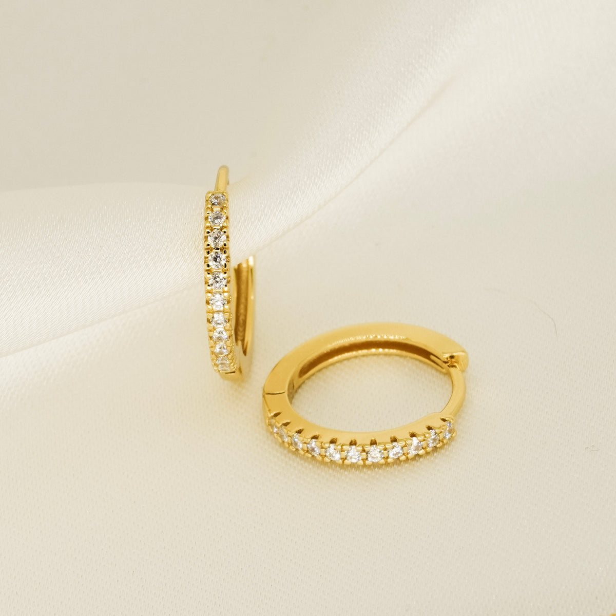 Gold hoop earrings adorned with glistening white stones perfect for gifting. From a small irish brand. 