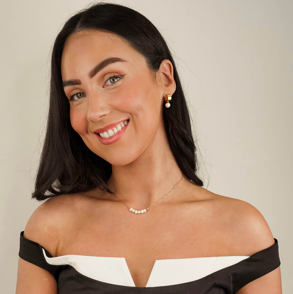 this photo shows a pearl necklace and matching  pearl earrings worn by a model. The pearls are bright and eye catching. The necklace has an elegant gold chain and the 6 freshwater pearls can move freely along it. 