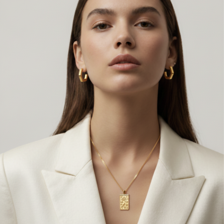 Woman wearing gold earrings and necklace against a neutral background