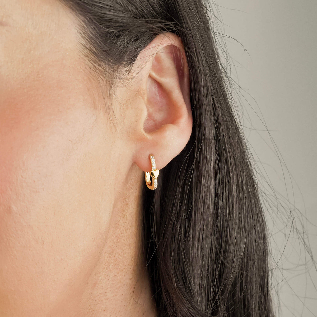 unique earrings with a dainty gold heart amid white zirconia stones. These hoop earrings have a unique shape. 
