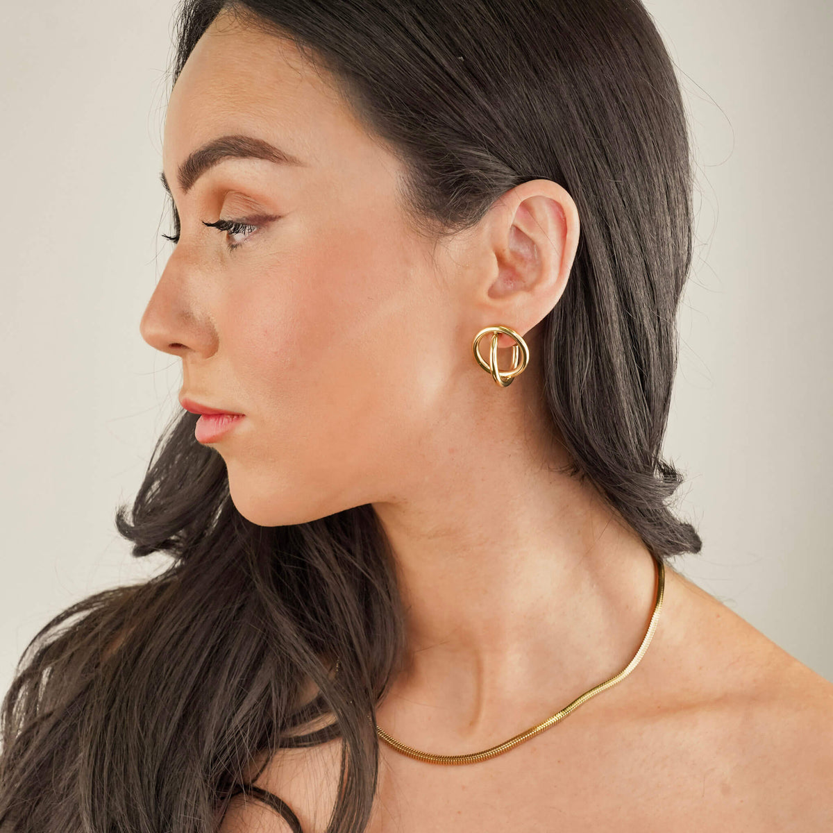 textured herringbone snake chain in gold plating available to shop at Mettle & Bloom. The Rhea chain is worn here by a model who has styled the Rhea chain with the Helix earrings. 