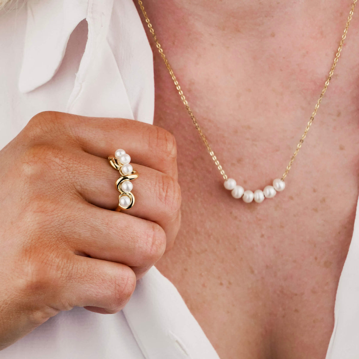 pearl necklace on a model. There are 6 pearls on a dainty stainless steel chain.  The model is also wearing the matching Oceanic Ring with 5 pearls. 