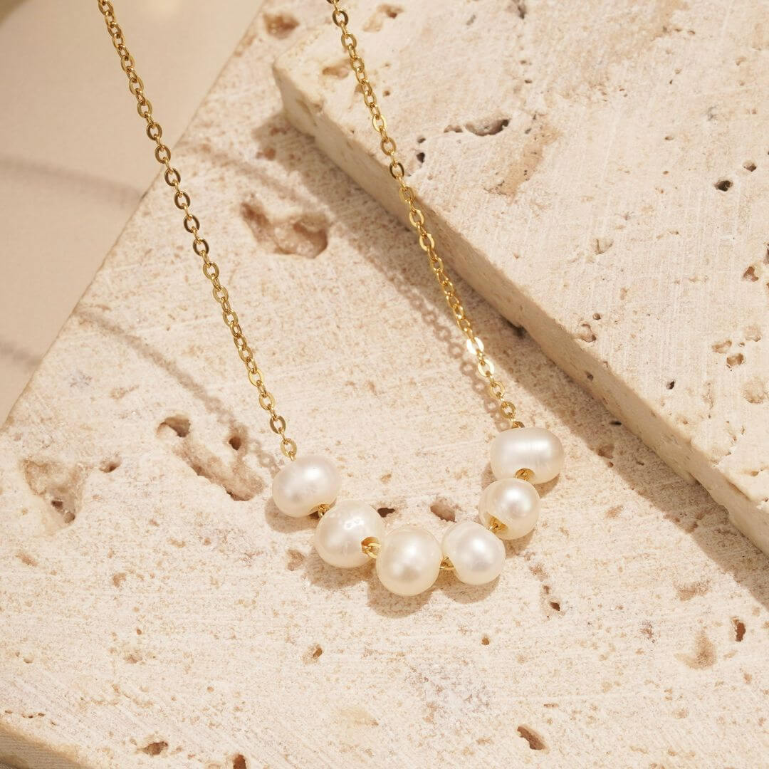 This Oceanic necklace is symbolic of life's ever changing tides. The 6 pearls roll freely on the gold chain, just like the water roll up on our shores. 