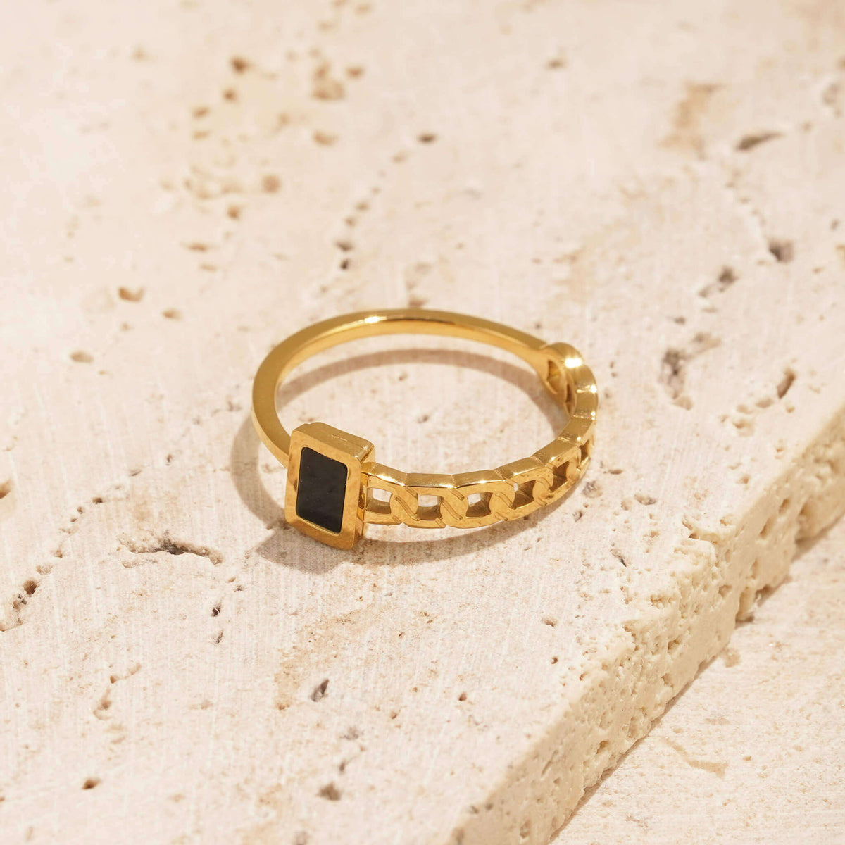 unique gold ring with a black stone. The rings band  has a rope texture on one side and a thin, minimal design on the other side. 