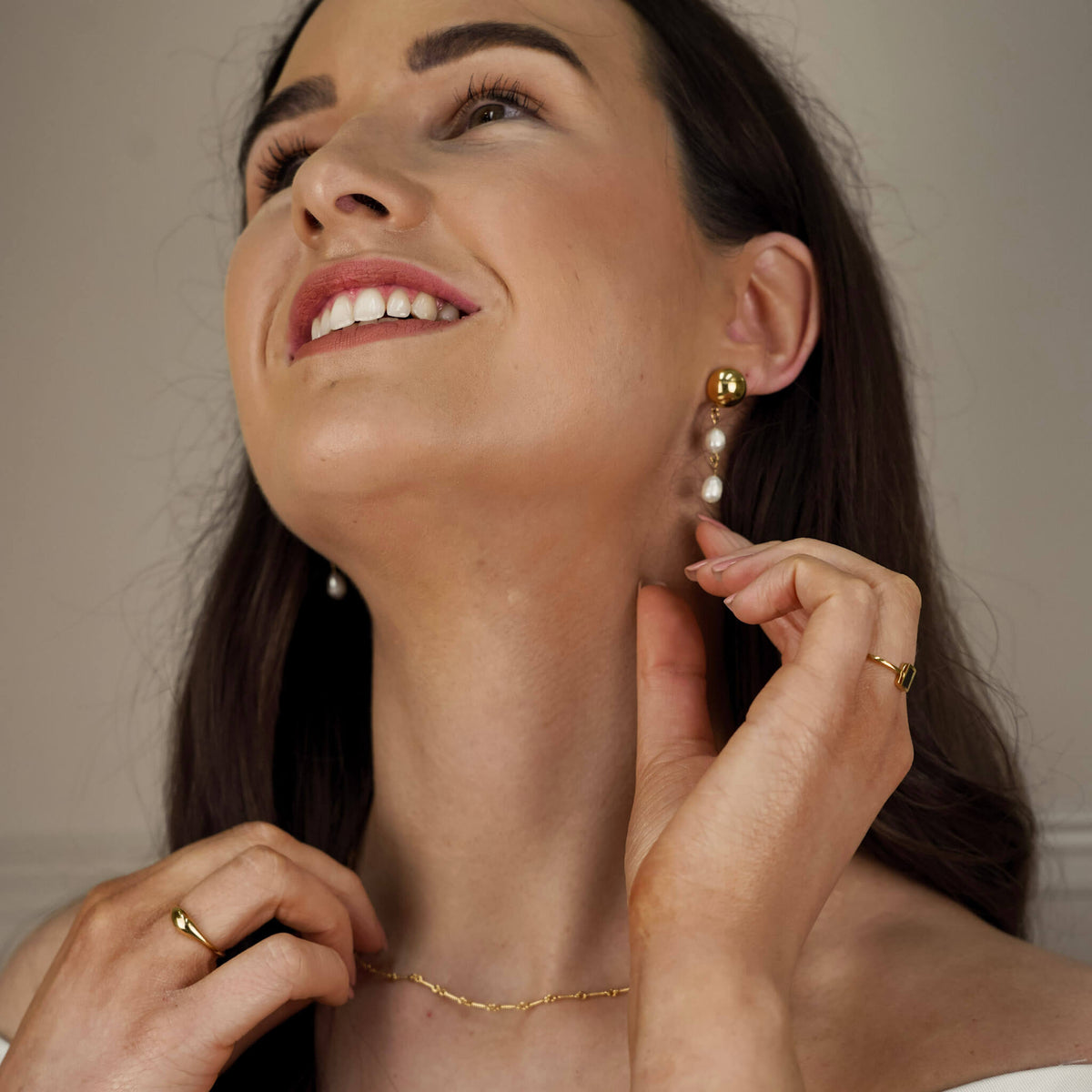Elegant pearl earrings worn by a brunette model. Two beautiful fresh water pearls hang from a gold stud. 