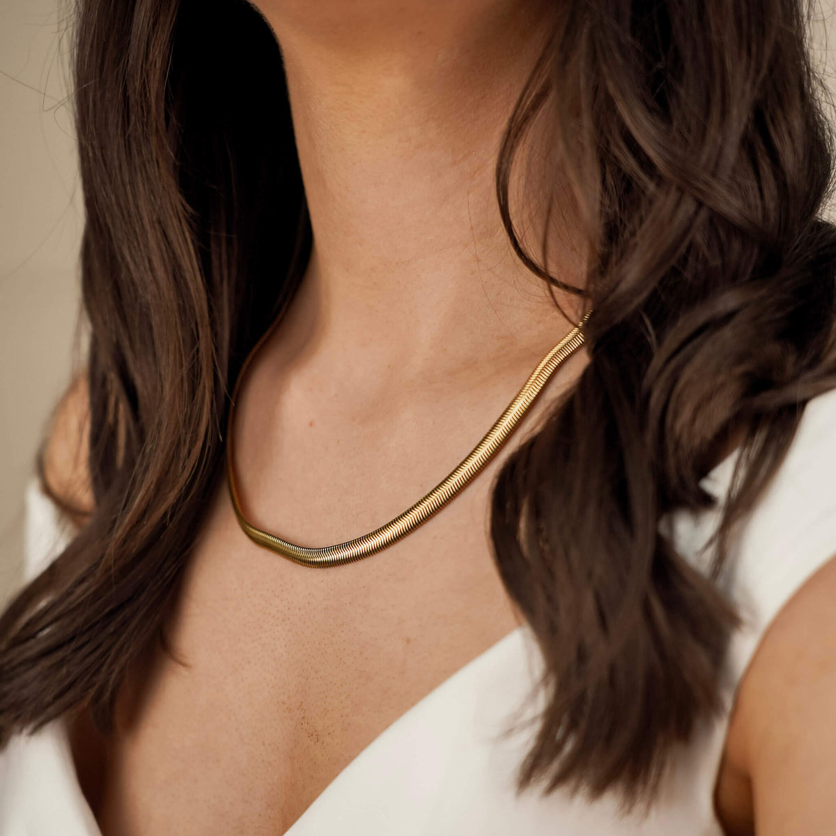 Elegant textured gold necklace worn by a brunette woman. The necklace is elegant and minimalistic making it timeless. 