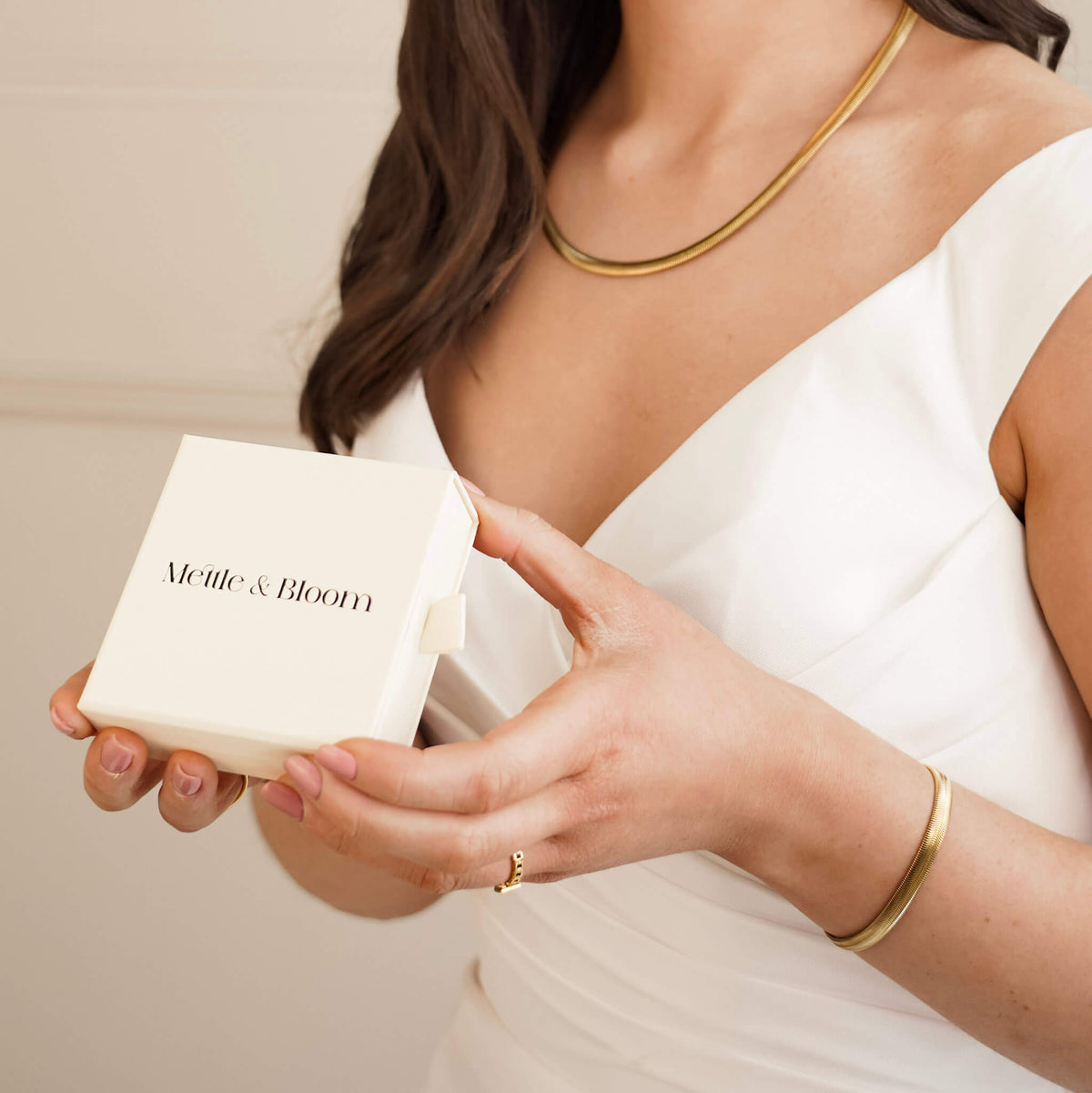 matching bracelet and necklace are worn by a bride in a wedding dress. She is wearing a mettle and bloom box and gifting jewelry to her bridesmaids. 