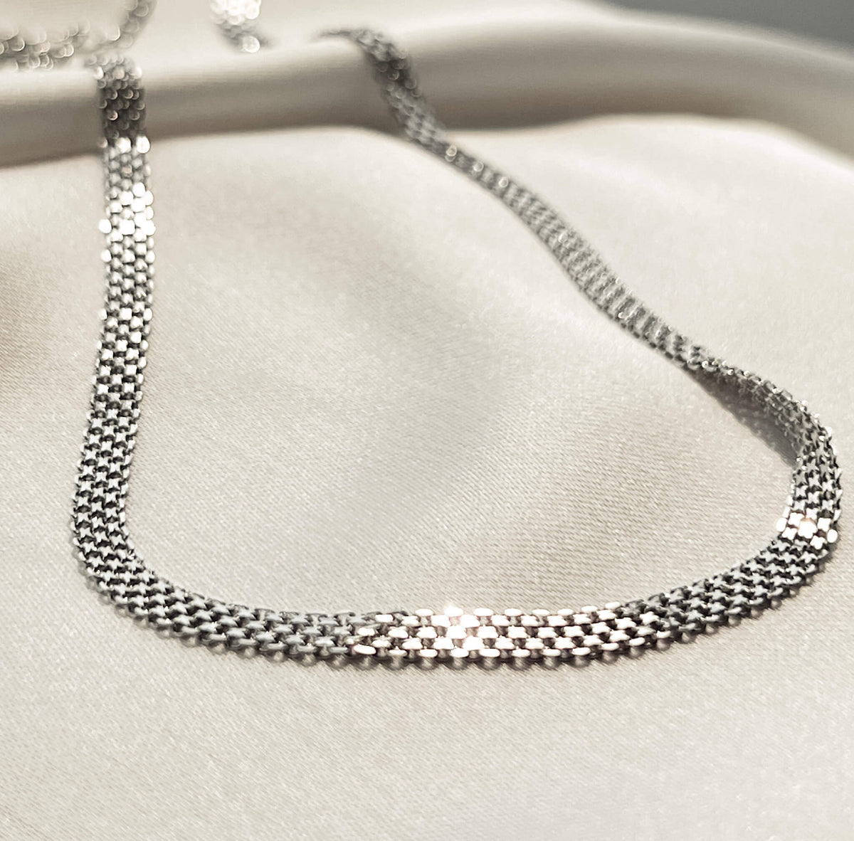 silver debonair chain on soft silk. The chain has a unique texture and design which folds in an elegant way. It has an extension clasp so it can be worn as a choker or extended. 
